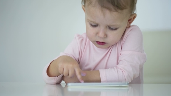 Young Child Plays On A Modern Smartphone In The Interior