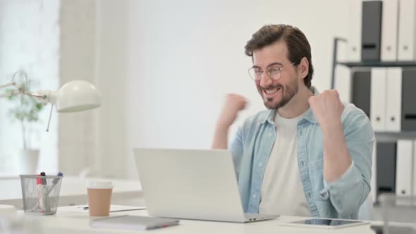 Successful Young Man Celebrating on Laptop at Work