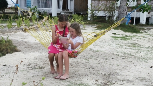 Girls In The Hammock With The Tablet On The Beach