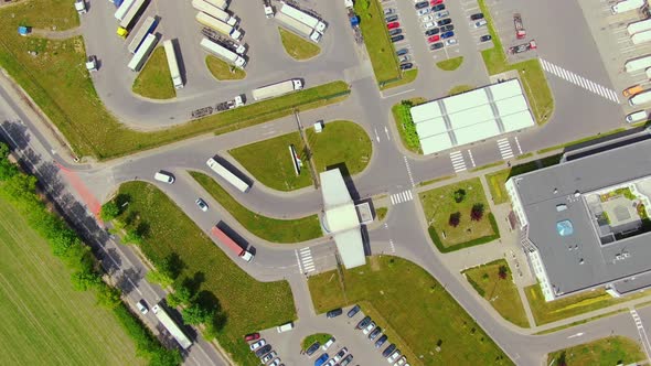 Semi truck with cargo trailer is travelling on a parking lot along a warehouse of a logistics park.