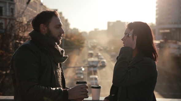 Couple Talking And Drinking Coffee On a  Bridge