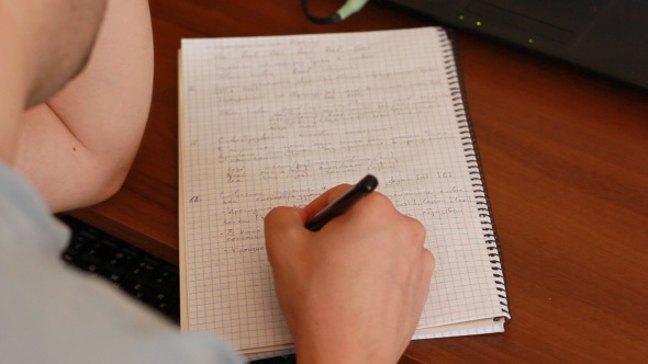 Student Studying And Writing Homework In His Exercise Book