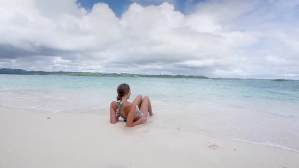 Young tanned brunette woman in bikini relaxing on beautiful beach with clear blue waters in Asia in