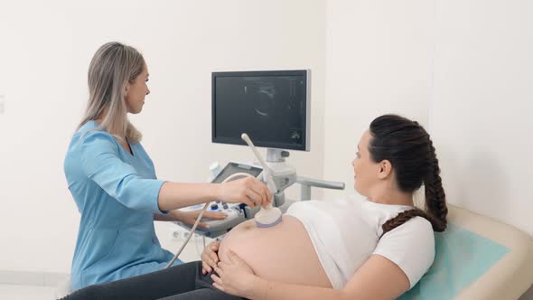 Happy Pregnant Woman Having Ultrasound Scanning at Clinic