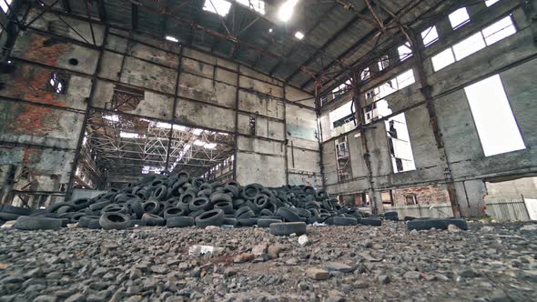 Big old empty factory with garbage and a pile of used rubber tyres inside.