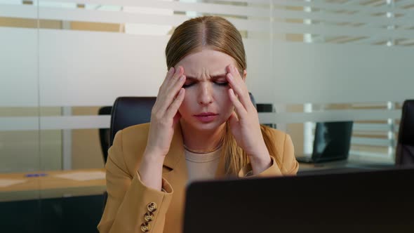 Caucasian businesswoman suffering from headache due to computer overwork,