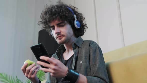 Young Man Listening to the Music and Dancing While Eatting an Apple