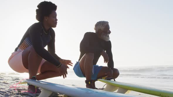 Happy african american couple with surfboards on sunny beach