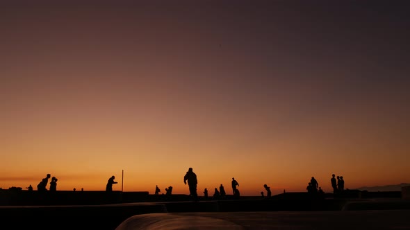 Silhouette of Young Jumping Skateboarder Riding Longboard, Summer Sunset Background. Venice Ocean