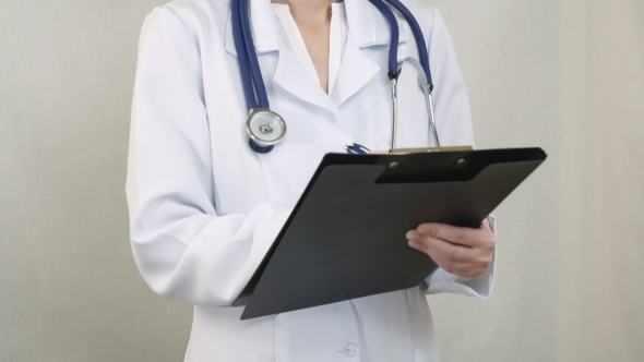 Doctor Standing And Filling The Document