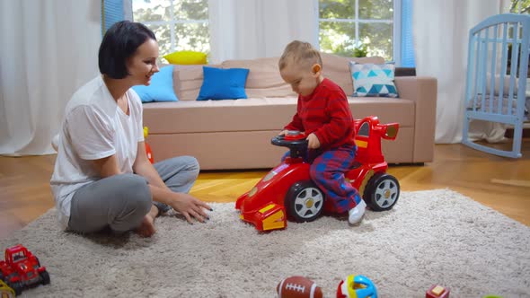 Caucasian Mother Watching Her Son Playing with Car Toy in Living Room