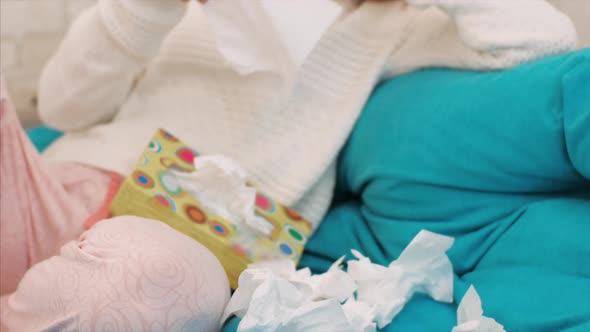 Sick Young Woman Sits of Sofa and Blowing Nose in Paper Tissue at Home