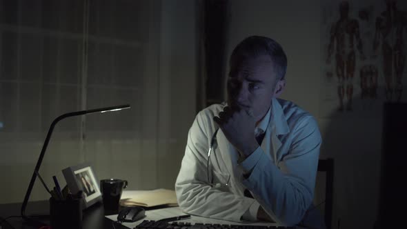 Depressed Doctor Working At His Office Desk