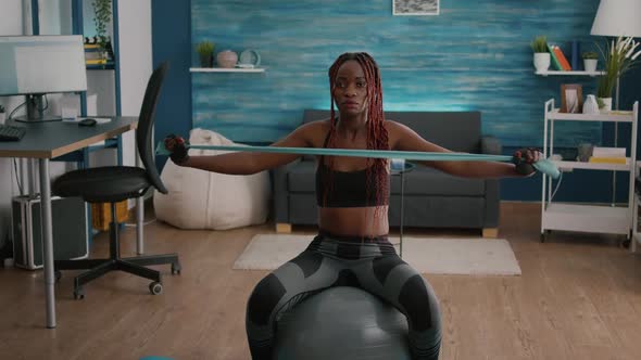 Fit Black Woman Doing Yoga Exercices Using Elastic Bands on Swiss Ball