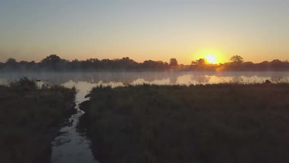 Aerial drone view of a sunset sunrise over a lake with fog in Africa