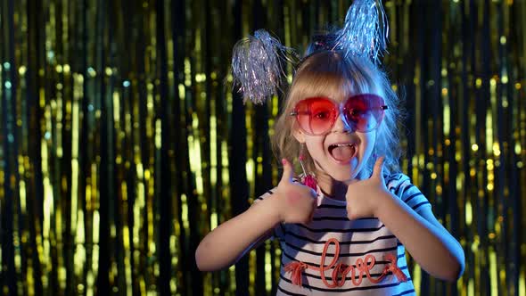 Stylish Teenager Kid Girl Standing on Backlit Blue Neon Lights and Points at Blank Space Agree Sign