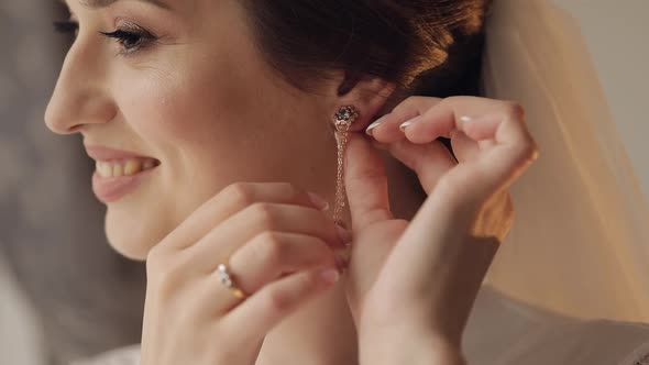 Bride in Boudoir Dress Puts on Earrings Wedding Morning Preparations Woman in Night Gown and Veil