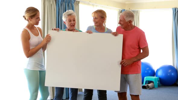 Trainer and senior citizens holding empty placard