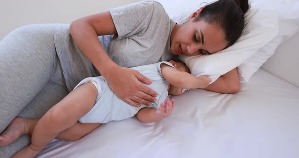 Young loving mother lying with her son on bed at home - Family and motherhood concept