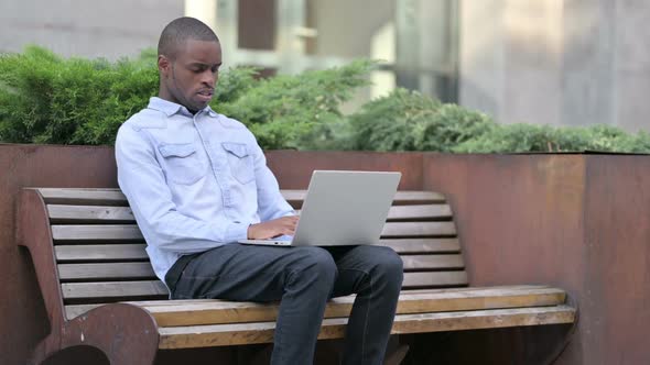 Sick Young African Man Using Laptop Coughing Outdoor