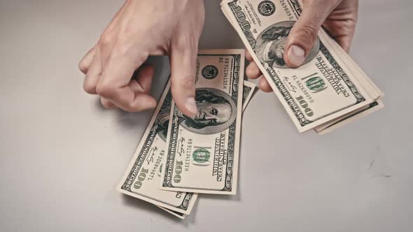 Male Hands Counting Old Hundred Dollar Banknotes on a White Table