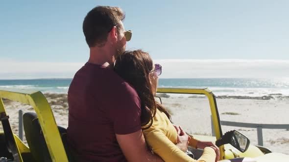 Happy caucasian couple sitting in beach buggy by the sea talking