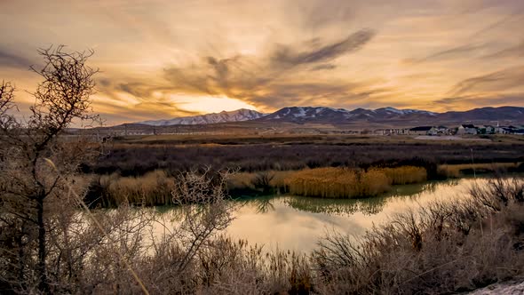 Wide angle sunset, day-to-night time lapse of the mountains in the background with a river in the fo