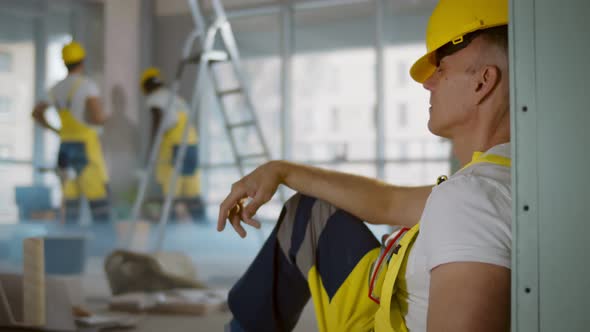 Caucasian Builder Worker Resting on Floor at Construction Site