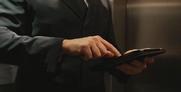 Businessman Using Tablet Computer in Elevator