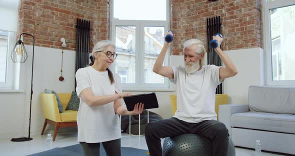 Old Man doing Exercises with Dumbbells and Repeating Exercises that His Positive Wife 