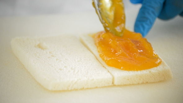 Chef Smearing Jam on Bread with a Spoon