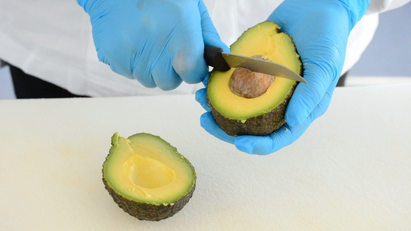 Chef Cuts an Avocado Fruit in Half with a Knife