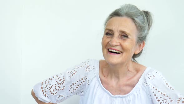 Beautiful Old Grandmother with Grey Hair and Face with Wrinkles is Looking at the Camera with Smile