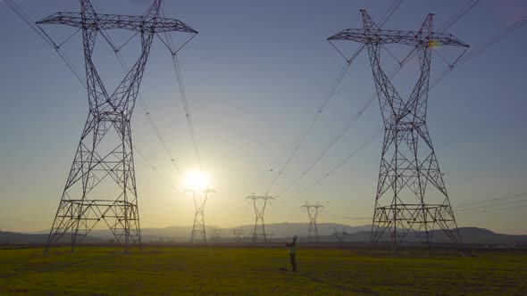 Engineer walking and working in front of electrical towers.