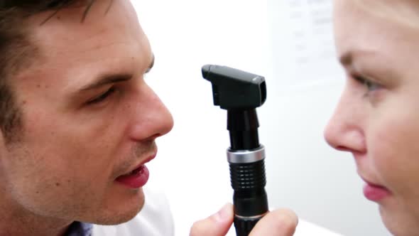 Optometrist examining female patient through ophthalmoscope