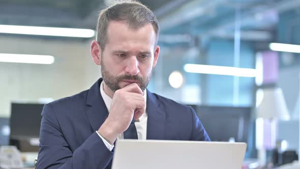 Portrait of Businessman Thinking and Working on Laptop