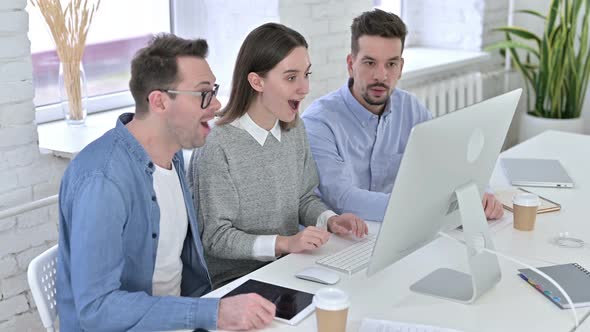 Attractive Creative Team Celebrating Success on Desk Top