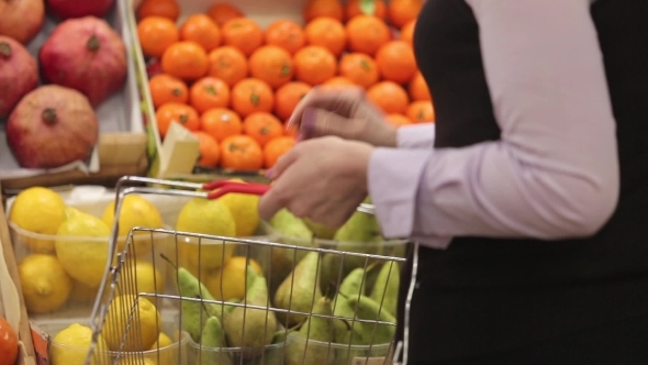 Woman With a Shopping Cart Makes Shopping At Fruit Store