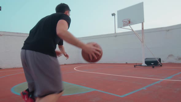 Following shot of two friends playing basketball one on one at outdoor court - good defedning