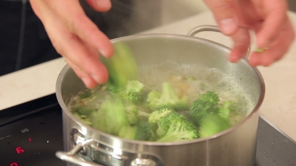 Chef Is Putting Broccoli Into a Boiling Pot Of Vegetable Soup 