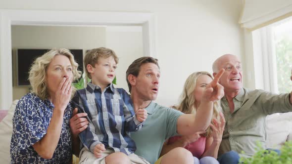 Happy caucasian family watching tv and supporting in living room