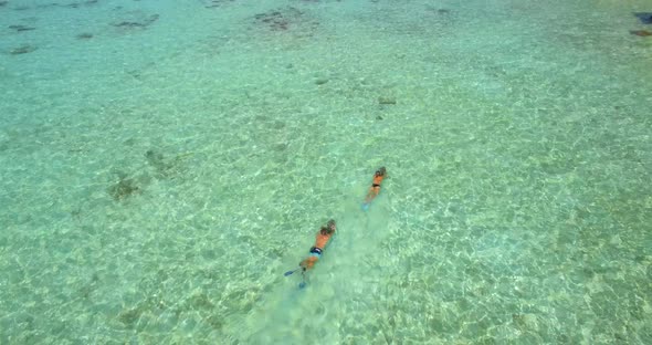 Aerial drone view of a man and woman couple with seascooters snorkeling near overwater bungalows