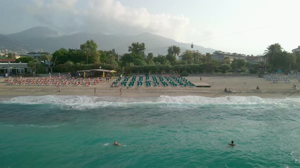 Beach Top View of Waves Crashing Against the Beach with People and Umbrellas on the Shore on a