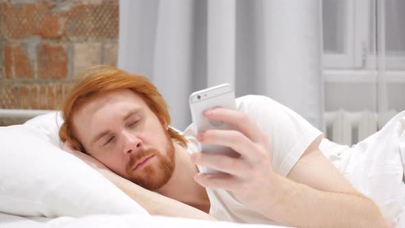 Man Lying in Bed and Browsing on Smartphone at Night