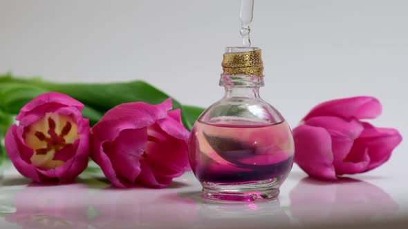 Perfumery. Drops falling from cosmetic pipette to glass bottle with perfume oil