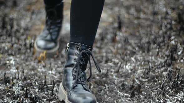 Close-up Front Shot of Walking Legs in Black Stylish Boots on Burnt Grass of Field in Sunny Weather