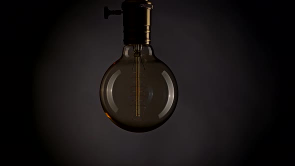 Power Outage in Dark Room. Blinking Edison Lamp Swinging on Wire. Black and Grey Background. UHD