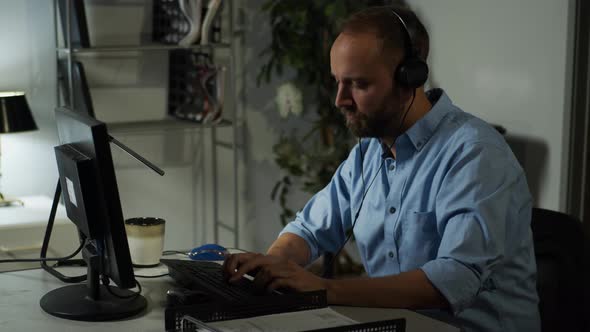 Male office working, working late while listening to music on headphones