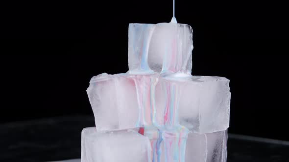 Multicolored Paint Spreads Over the Surface of the Ice Cubes and Flows Down Onto the Plane