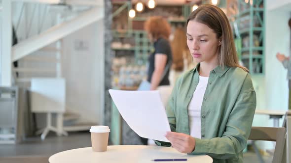 Excited Woman Reading Documents and Celebrating in Cafe